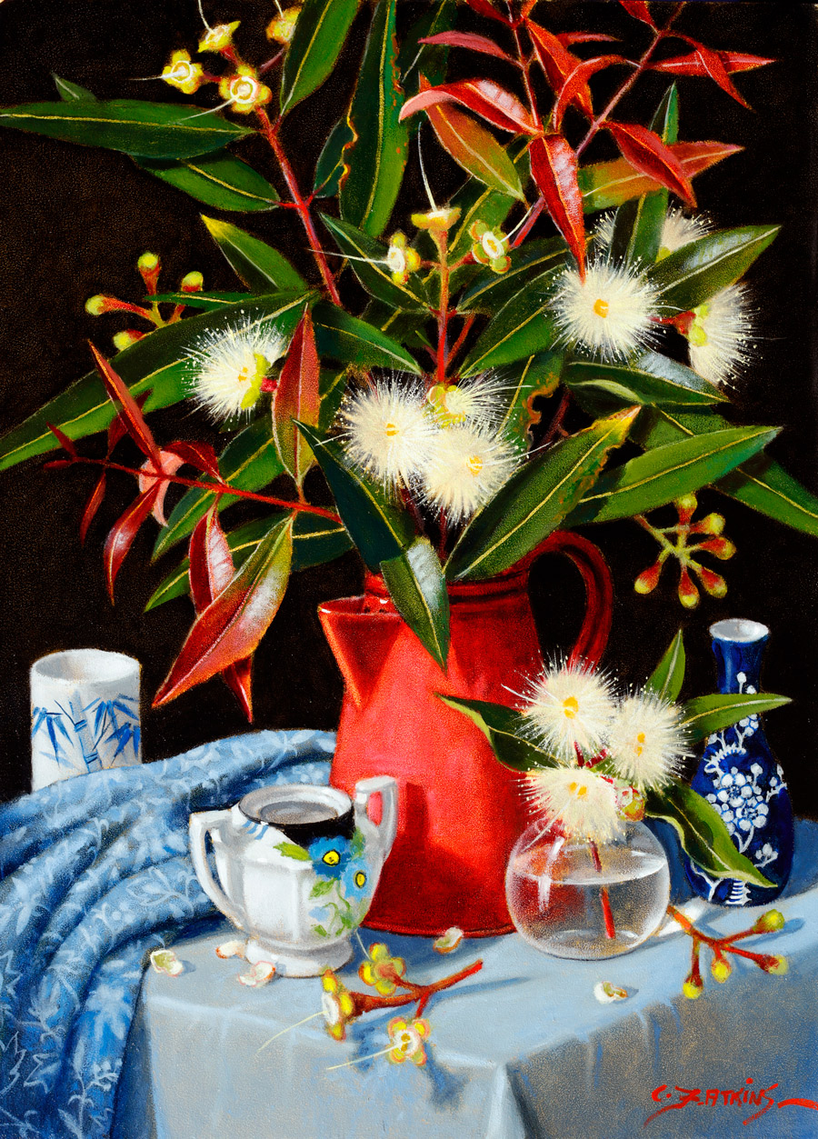 Leaves and flowers from a rainforest tree are in a red enamel jug.