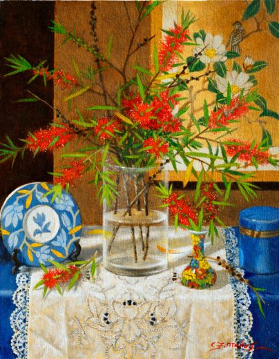 A glass vase of red flowers stand on a lace cloth.