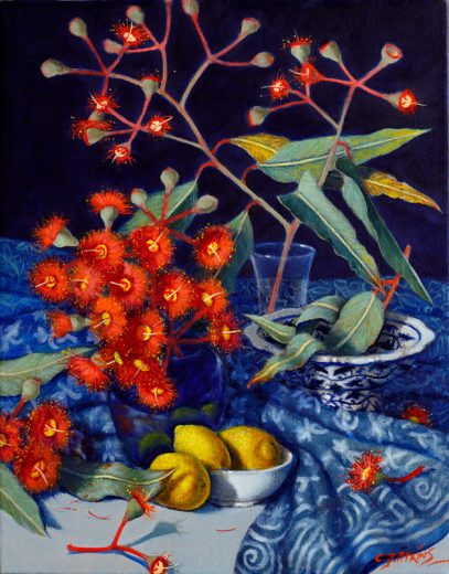 Gum blossoms and yellow lemons are set on a blue cloth.