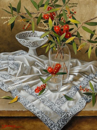 Bottlebrush flowers and a lace cloth stand on a table.