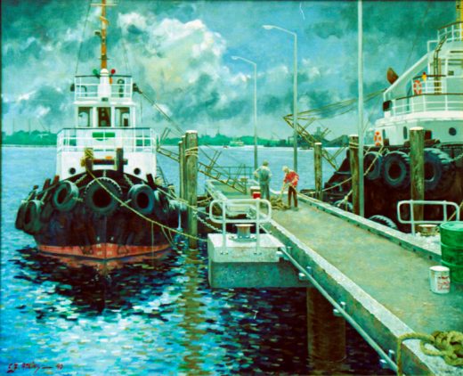 Two solidly-built tugs are tied up at a jetty.
