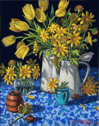 Two jugs of yellow flowers stand on a patterned tablecloth.