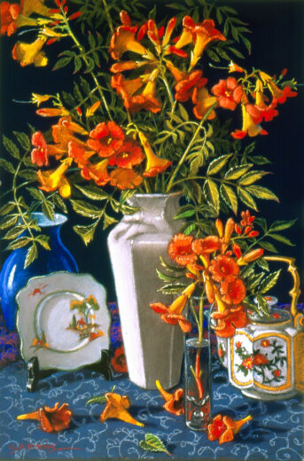 A six sided, white vase holds orange trumpet flowers.