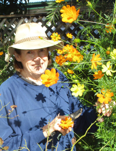 The artist stands next to tall cosmos plants.