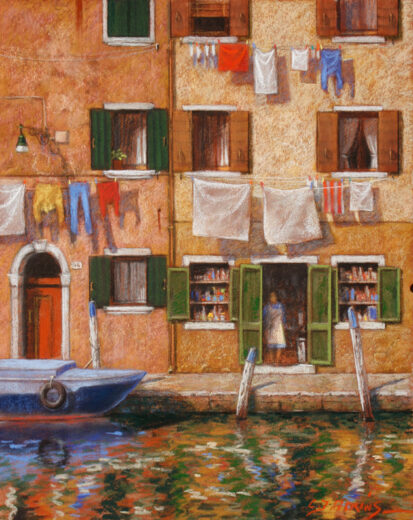 Washing hangs above a canal in Venice. The windows have green wooden shutters.