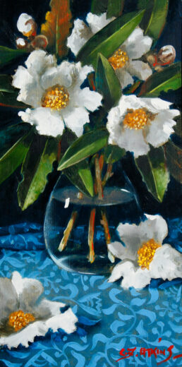 White flowers in a glass vase standing on a blue-patterned tablecloth.