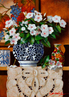 Phlox flowers in a blue and white vase stand on a shelf.