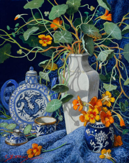 A teapot with a dragon motif is accompanied by a cream vase of nasturtiums.