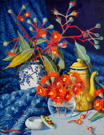 A yellow coffee pot is accompanied by two vases of red gum flowers.