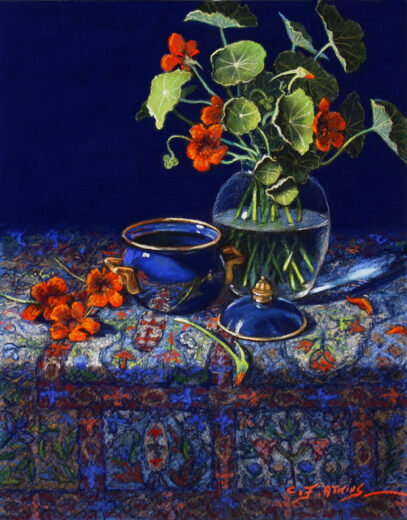 Nasturtiums in a glass vase stand on an intricate carpet.