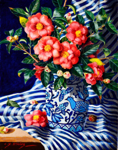 Winter blooming red camellias are in a blue and white patterned jug. The jug stands on a striped cloth.