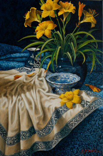 A tablecloth with many folds is in front of a pot of yellow-flowering lilies.