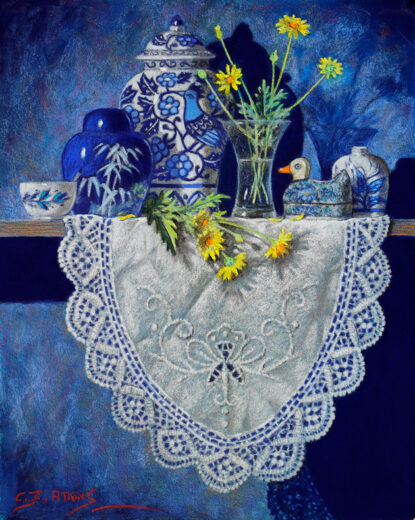 A doily hangs down from a shelf. On the doily is a small duck and a ceramic vase with a bird motif.