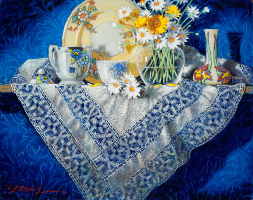 A lace tablecloth hangs down from a shelf. A plate, a bowl of flowers and other items rest on the shelf.