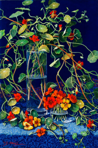 A tall glass vase is the centre of a colourful mass of tendrils and leaves.