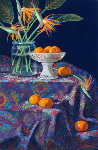 A bowl of mandarins and a vase of Bird of Paradise flowers stand on a patterned tablecloth. 